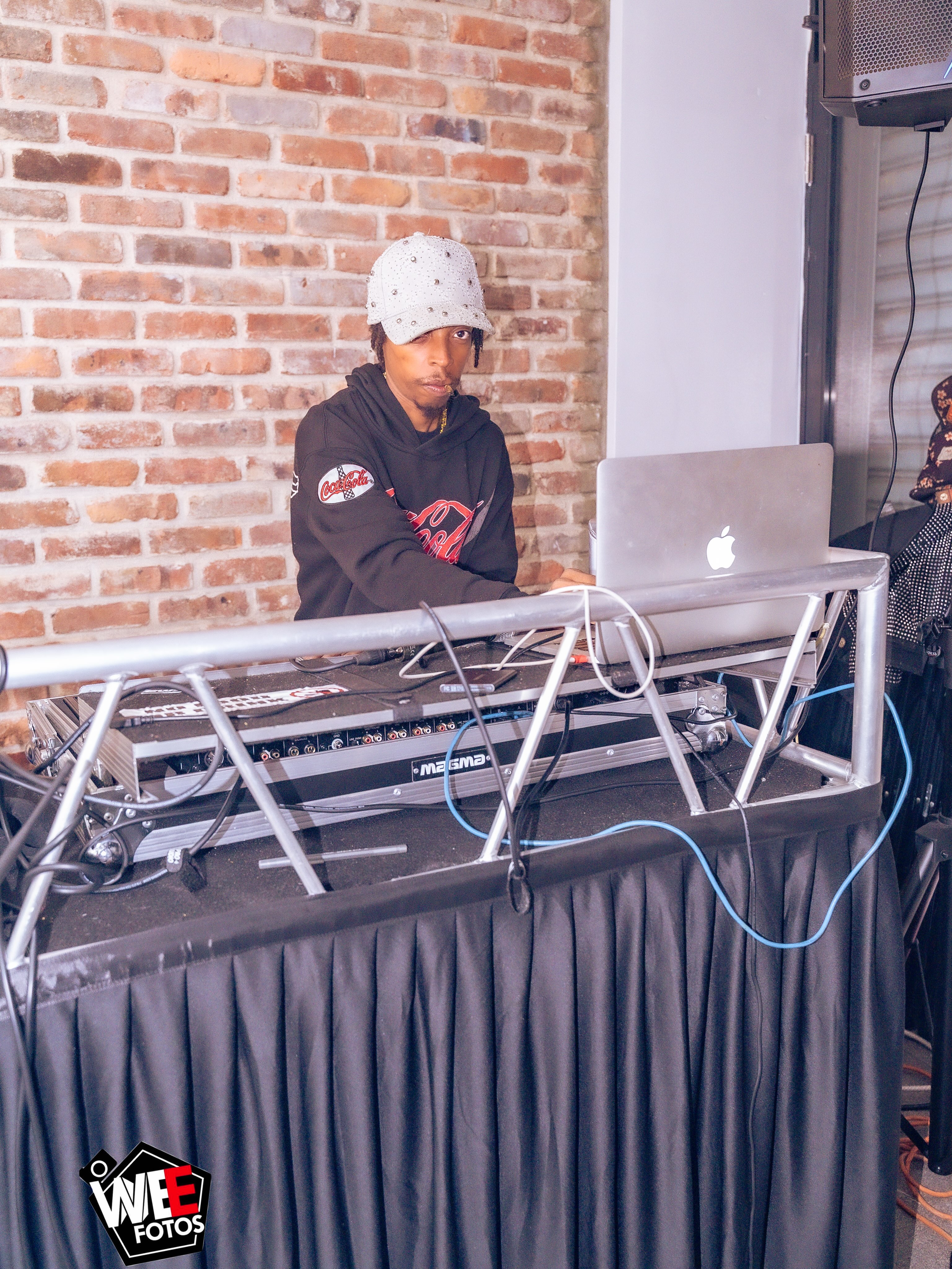 Shorts Temper behind the DJ setup wearing a hat